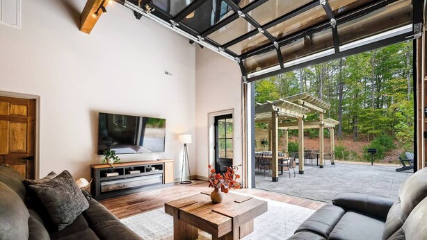 A modern living room with a large TV, comfortable seating, and a view of the outdoor patio. - 5 King Beds | Sleeps 18 | Pickleball | Brew Trail (Nelson County)