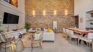A spacious living area with a brick wall, a flat-screen TV, a dining table, and comfortable seating. - Elegant/Modern Apt in Poblado - Morph 1201 (Medellín)