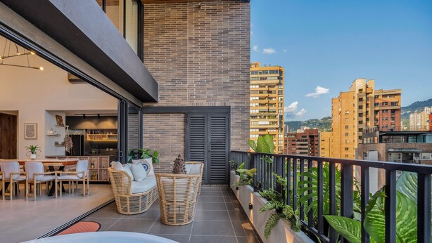 A modern apartment with a balcony, furnished with wicker furniture and potted plants. - Elegant/Modern Apt in Poblado - Morph 1201 (Medellín)