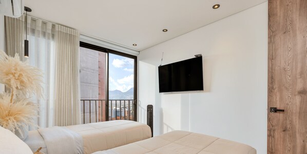 A modern hotel room with a large window, a flat-screen TV, and a wooden door.