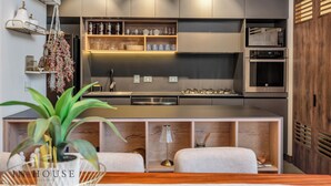 A modern kitchen with built-in appliances, wooden shelves, and a central island. - Elegant/Modern Apt in Poblado - Morph 1201 (Medellín)