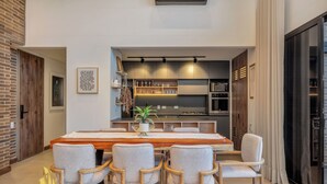 A modern dining area with a wooden table, six chairs, and a kitchen in the background. - Elegant/Modern Apt in Poblado - Morph 1201 (Medellín)