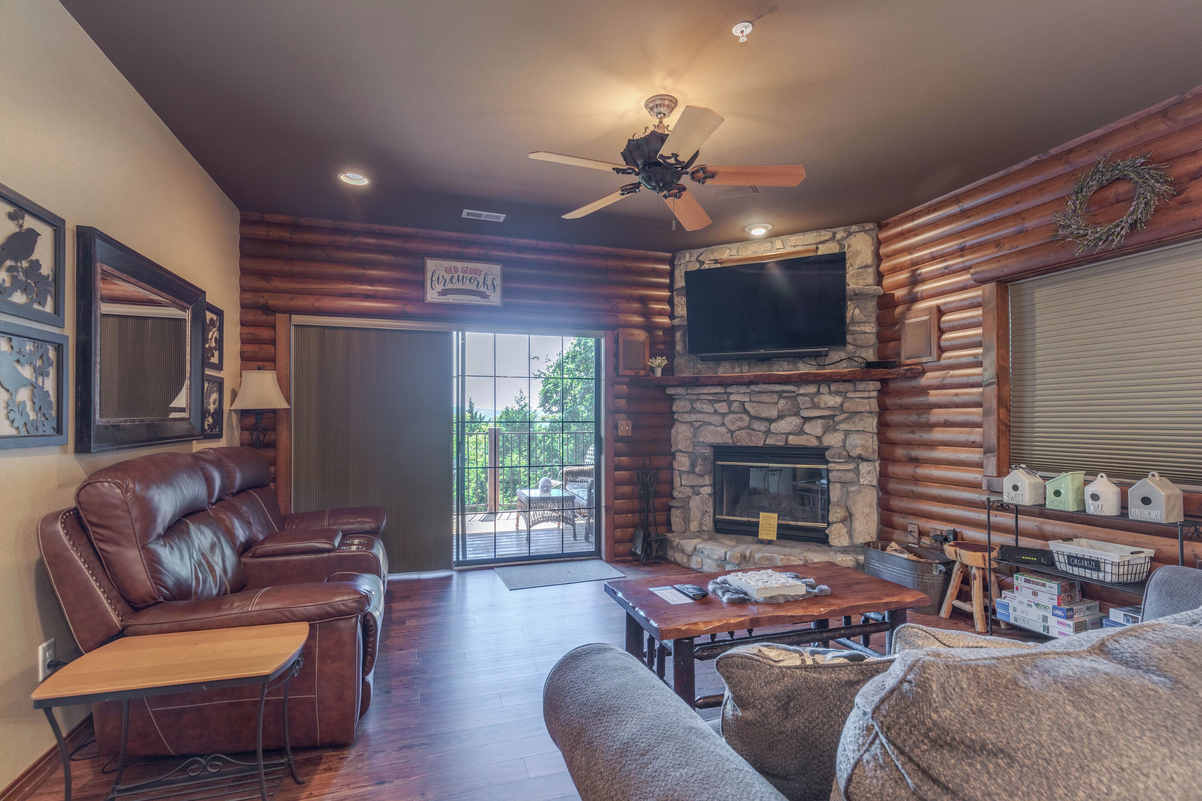 A cozy living room with a stone fireplace, leather recliner, and a flat-screen TV mounted above it.