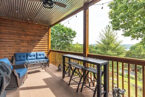 A covered outdoor area with a wooden deck, a blue sofa, a small table, and a dog statue.