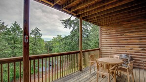 Une terrasse en bois avec une table et des chaises, donnant sur une zone boisée.