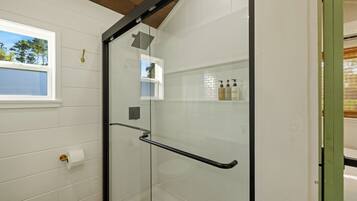 Een moderne badkamer met een douchecabine van glas, een toilet en een raam met uitzicht op de omgeving.