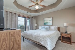 Ein Schlafzimmer mit Bett, Schreibtisch, Deckenventilator, Fenster und Nachttisch.