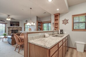 Eine geräumige Küche mit Granit-Arbeitsplatten, Holzschränken, einem Kamin aus Naturstein und einem Essbereich mit Ledersofa und Holzsesseln.