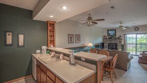 A kitchen with a central island, wooden cabinets, and a dining area with chairs.