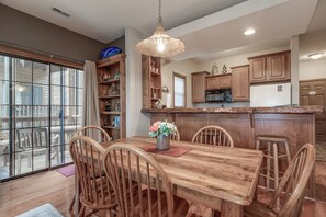 Un coin repas avec une table et des chaises en bois, un luminaire suspendu et des armoires en bois.