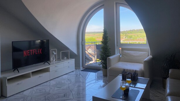 Un salon moderne avec une grande télévision, un canapé blanc et une table basse.