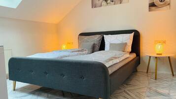Een moderne slaapkamer met een bed, een klein nachtkastje, een wandlamp en een dakvenster.