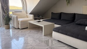 Un salon moderne avec un canapé blanc, un canapé gris foncé, une table basse blanche et une plante en pot.