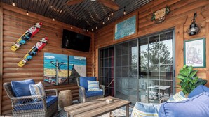 A log cabin interior with wicker furniture, a wooden table, and a large window. - 1BR Village At Indian Point 1303 near SDC-Free Tickets Daily up to $500 Value (Branson)