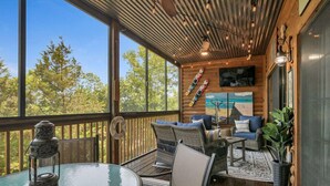 A wooden deck with a glass table and chairs, a mounted ski rack, and a painting of a boat on the wall. - 1BR Village At Indian Point 1303 near SDC-Free Tickets Daily up to $500 Value (Branson)