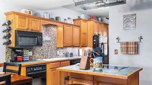 Una cucina con mobili in legno, un forno a microonde, una macchina da caffè e un lavello.