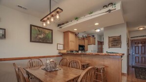 A dining area with a wooden table and chairs, a kitchen with wooden cabinets, and a bar area.