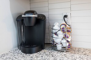 A coffee maker and a basket of disposable cups on a kitchen counter. - Dolly's Rooftop Igloo (Nashville)