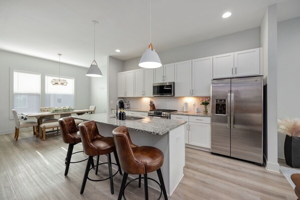 A modern kitchen with white cabinets, stainless steel appliances, and a central island with bar stools.