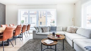 A modern living room with a sofa, coffee table, and dining area with chairs.