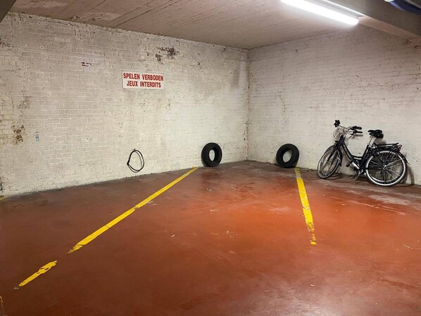 A parking garage with a bicycle, two tires, and a sign in French. - Elegant Coastal Retreat in Knokke-Heist (Knokke-Heist)