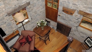 Una habitación con paredes de piedra, una mesa de madera, una silla, un sofá y una puerta.