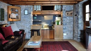 Una sala de estar acogedora con chimenea, pared de piedra y techo de madera.
