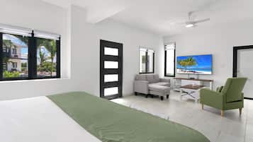 Una habitación de hotel moderna con una cama, una silla verde, un sofá, un escritorio y un televisor.