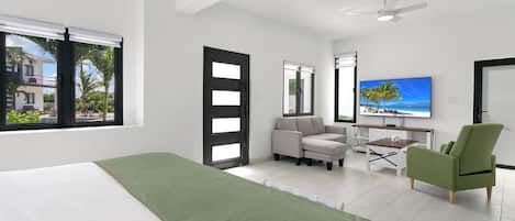 Una habitación de hotel moderna con una cama, una silla verde, un sofá, un escritorio y un televisor.