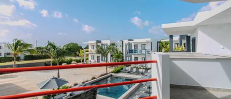 A modern hotel with a rooftop pool, outdoor seating, and a clear view of the surrounding buildings.