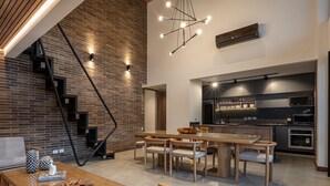 A modern kitchen with built-in appliances, a dining area with a wooden table and chairs, and a staircase with exposed brick walls. - Exclusivity in Poblado/Jacuzzi-Morph 1601 (Medellín)