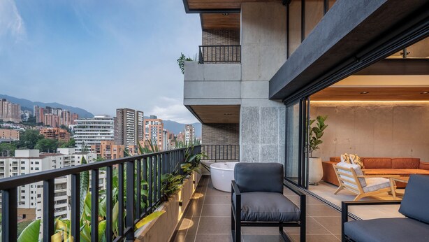 A modern balcony with a view of a cityscape, featuring a sofa, a coffee table, and potted plants. - Exclusivity in Poblado/Jacuzzi-Morph 1601 (Medellín)