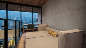 A modern living room with a sofa, a chair, and a view of a cityscape through large windows. - Exclusivity in Poblado/Jacuzzi-Morph 1601 (Medellín)