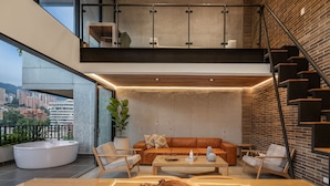 A modern living space with a large window, a seating area with a sofa and chairs, a coffee table, and a staircase. - Exclusivity in Poblado/Jacuzzi-Morph 1601 (Medellín)
