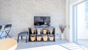 Una sala de estar moderna con pared de ladrillo, un televisor de pantalla plana, un sofá, una mesa de centro y una estantería con cestas.