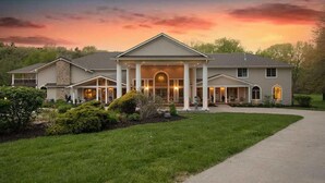 A large, two-story house with a covered front porch, multiple windows, and a well-maintained lawn.