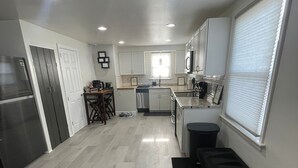 A modern kitchen with a refrigerator, stove, sink, and cabinets. There is a dining area with a table and chairs. - Charming 2-bedroom house with WiFi, AC in enjoyable Lancaster (Lancaster)