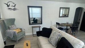 A modern living room with a grey sofa, a wooden coffee table, and a dining area with a table and chairs. - Charming 2-bedroom house with WiFi, AC in enjoyable Lancaster (Lancaster)