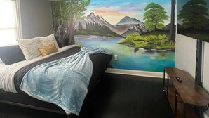 A bedroom with a bed, a nightstand, a window, and a mural of a landscape. - Charming 2-bedroom house with WiFi, AC in enjoyable Lancaster (Lancaster)