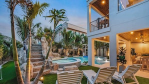 A modern house with a swimming pool, outdoor seating, and a rock formation. - New - Private Beach Access/Zip Line & Waterslide (Sarasota)