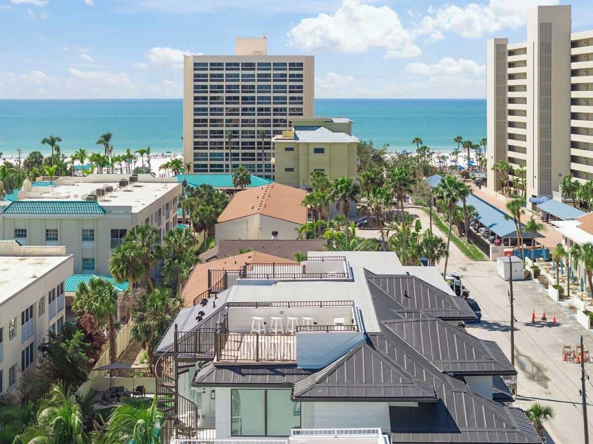 A hotel with multiple buildings, a rooftop pool, and a view of the ocean.
