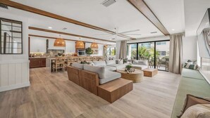 A spacious living area with a large sectional sofa, a dining table, and a kitchen in the background. - New - Private Beach Access - Pool Bar/Volleyball (Sarasota)