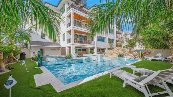 A multi-story hotel with a swimming pool, outdoor seating, and palm trees.