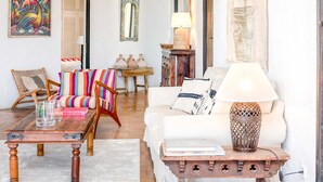 A living room with a white sofa, colorful striped cushions, a wooden coffee table, and a lamp. - CASA AMAPOLA (Sant Josep de Sa Talaia / San Jose)