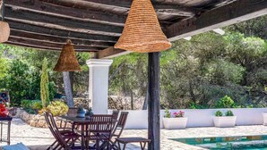 An outdoor patio with a pool, wooden furniture, and hanging wicker lamps. - CASA AMAPOLA (Sant Josep de Sa Talaia / San Jose)