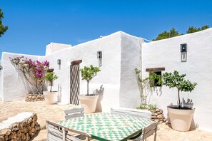 A courtyard with a checkered table, potted plants, and white walls. - CASA AMAPOLA (Sant Josep de Sa Talaia / San Jose)