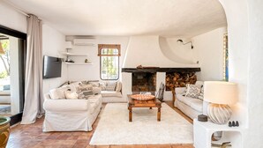 A living room with a fireplace, white sofas, a coffee table, and a TV mounted on the wall. - CASA AMAPOLA (Sant Josep de Sa Talaia / San Jose)