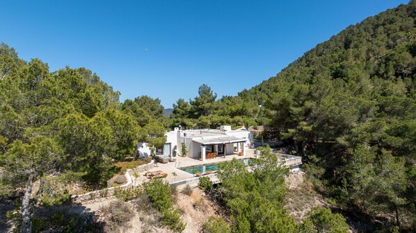 A modern villa with a pool, surrounded by dense forest and hills. - CASA AMAPOLA (Sant Josep de Sa Talaia / San Jose)