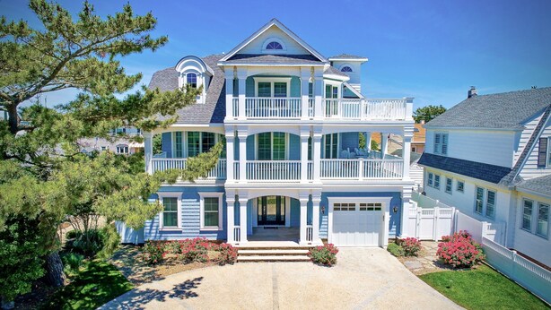 A two-story house with a front porch, a garage, and a well-maintained lawn. - Spacious 6BR Beach Home With Elevator Heated Pool - Ideal for Family Vacations (Brigantine)