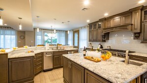 A modern kitchen with granite countertops, dark wooden cabinets, stainless steel appliances, and pendant lighting. - Spacious 6BR Beach Home With Elevator Heated Pool - Ideal for Family Vacations (Brigantine)